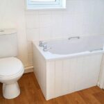 Bathroom with tub and wooden floors in 2 bed house to rent in Milton Keynes